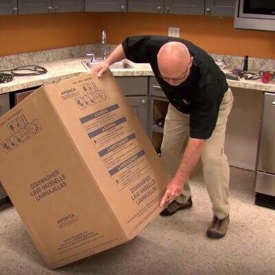 A person tilting a dishwasher cardboard box on its side
