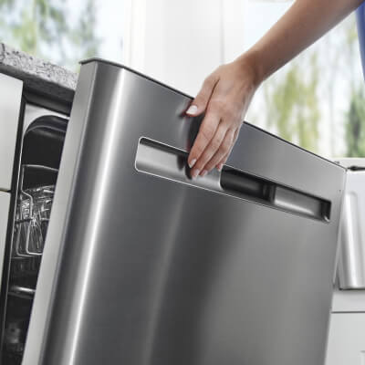 A close up of a hand closing a dishwasher door