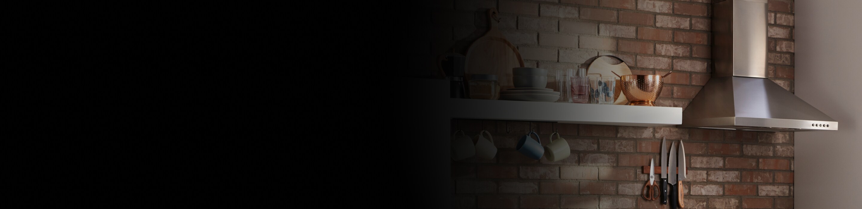 Stainless steel range hood on a brick kitchen wall