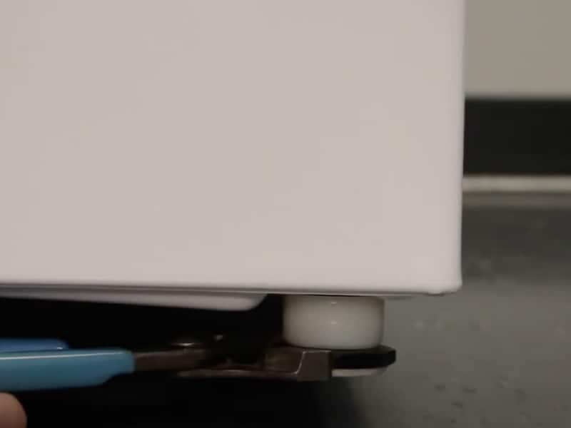 A man adjusting the leveling feet of a Maytag® washing machine. A man adjusting the leveling feet of a Maytag® washing machine.