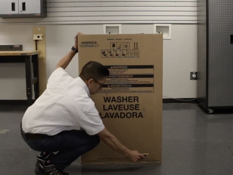 A man unpacking a Maytag® top load washing machine. A man unpacking a Maytag® top load washing machine.