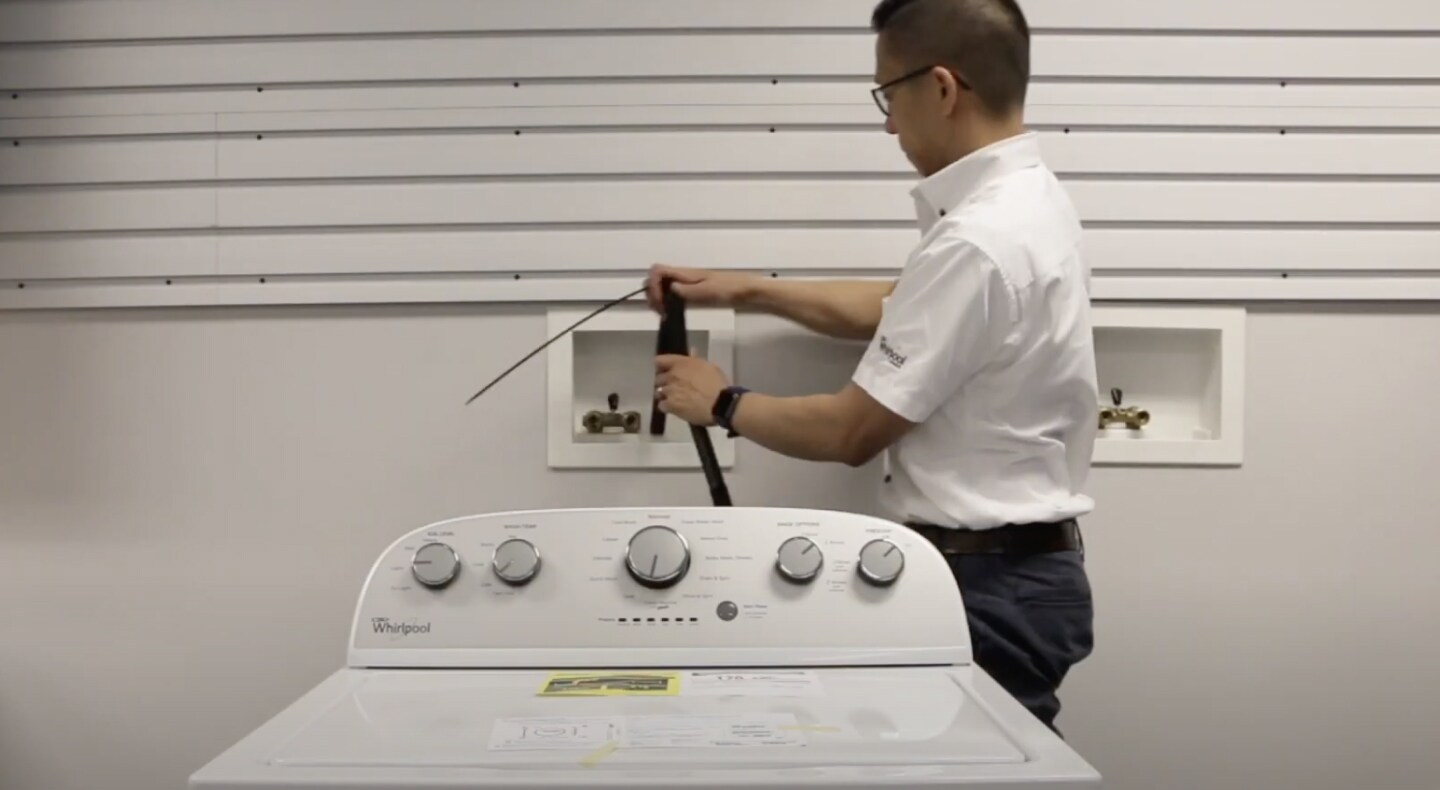 A man placing a drain hose into the standpipe of a Maytag® washing machine. A man placing a drain hose into the standpipe of a Maytag® washing machine.