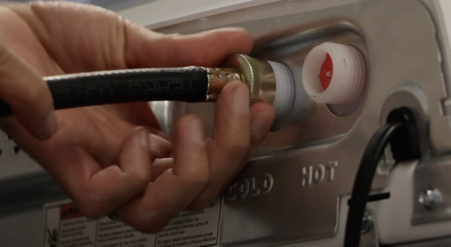 A man connecting inlet hoses to a Maytag® washing machine. A man connecting inlet hoses to a Maytag® washing machine.