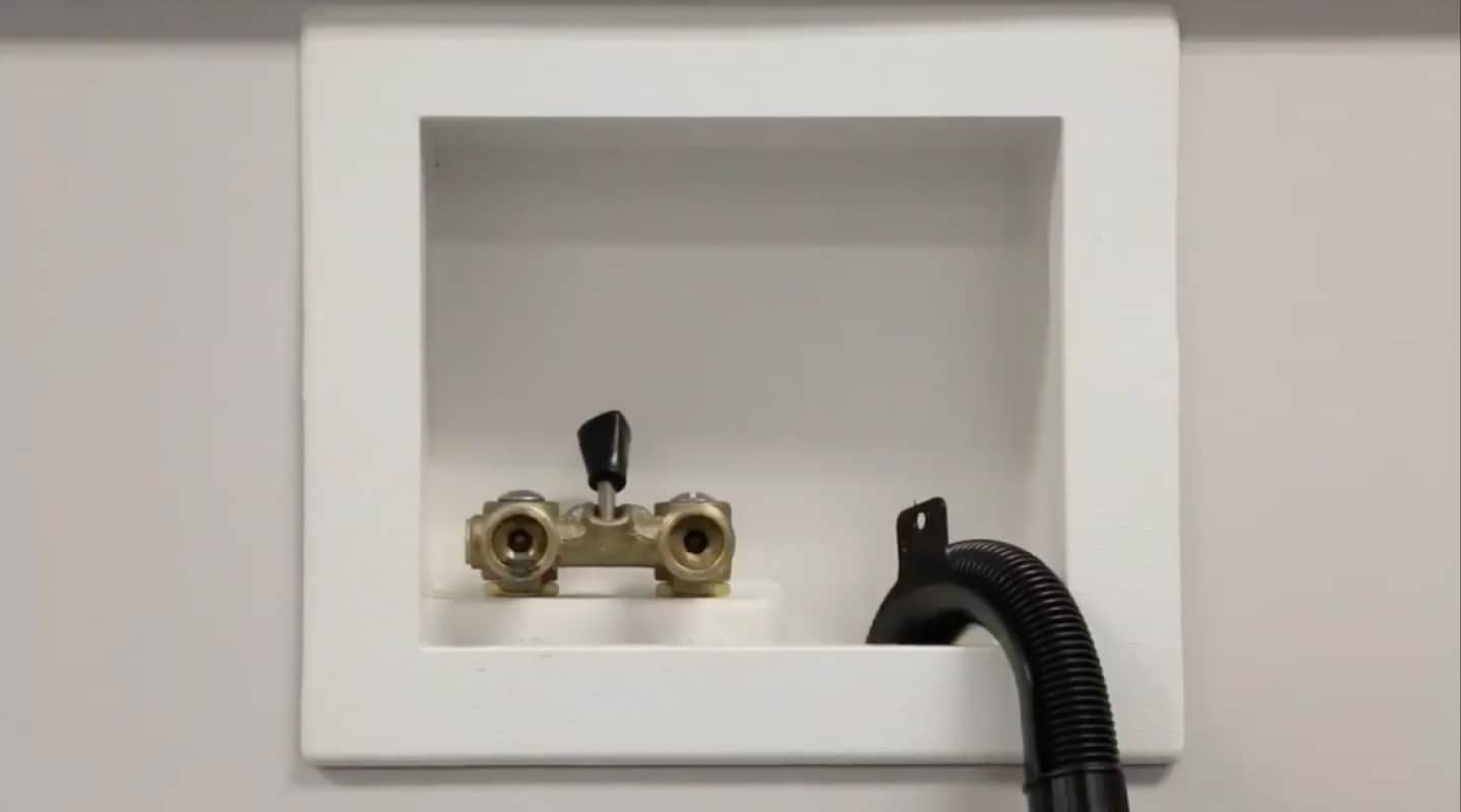 A black drain hose and water valves.