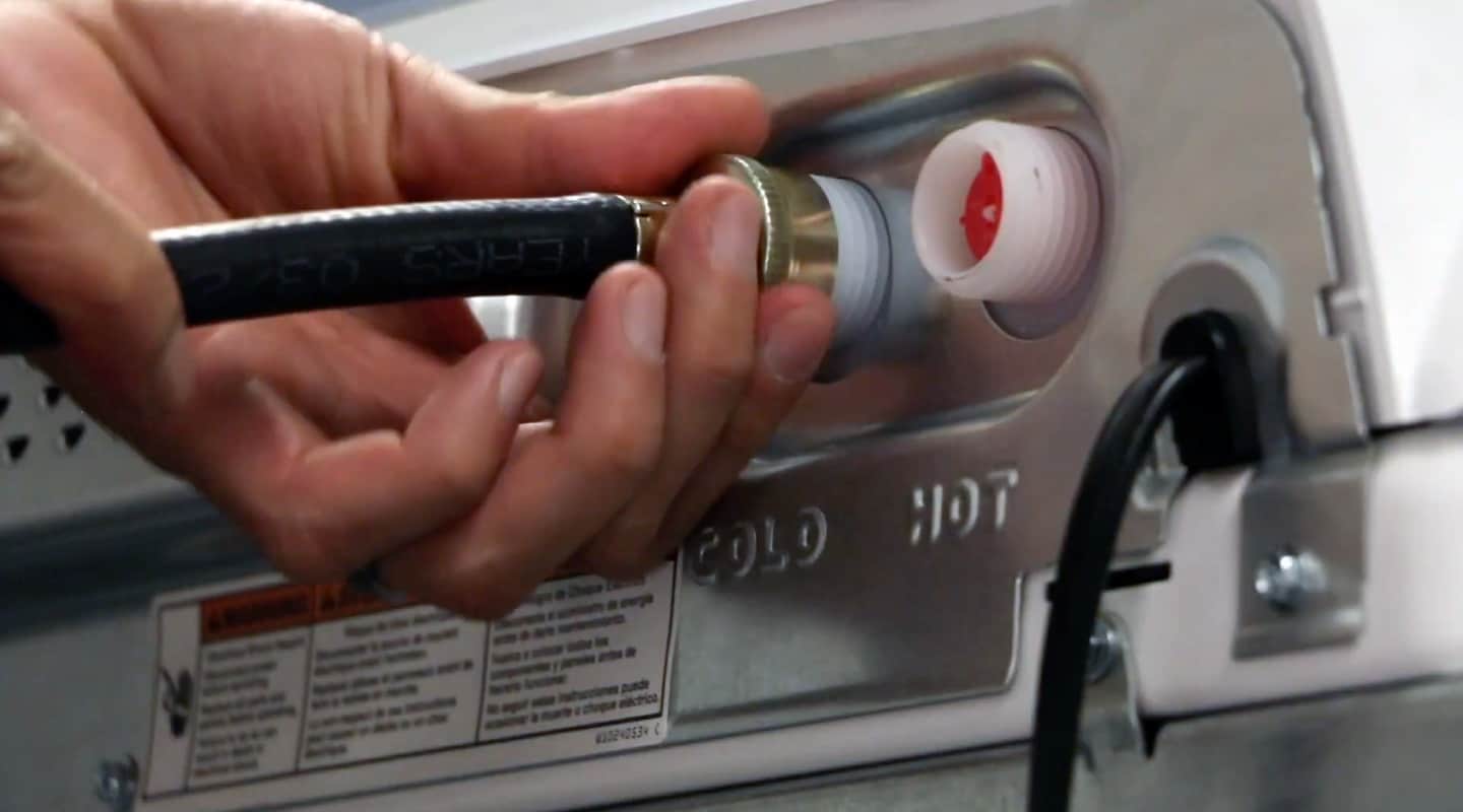 Person connecting drain hose to the back of a washer.