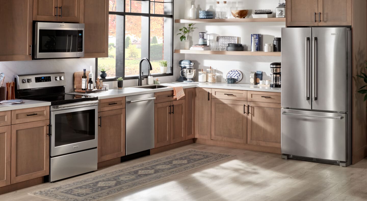 The inside of a kitchen with wood cabinetry and stainless steel appliances