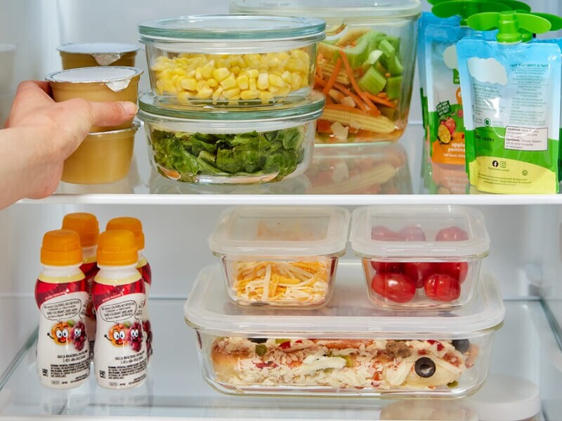 Person stacking groceries inside a refrigerator
