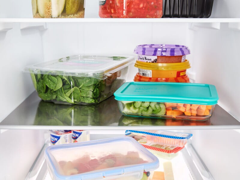 Containers of fresh ingredients stored on fridge shelves