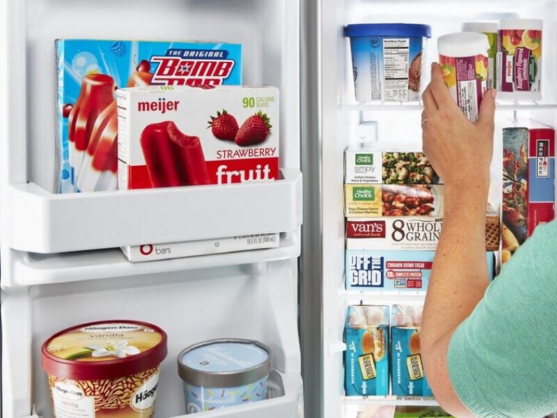 A woman removing an item from a side-by-side fridge freezer compartment
