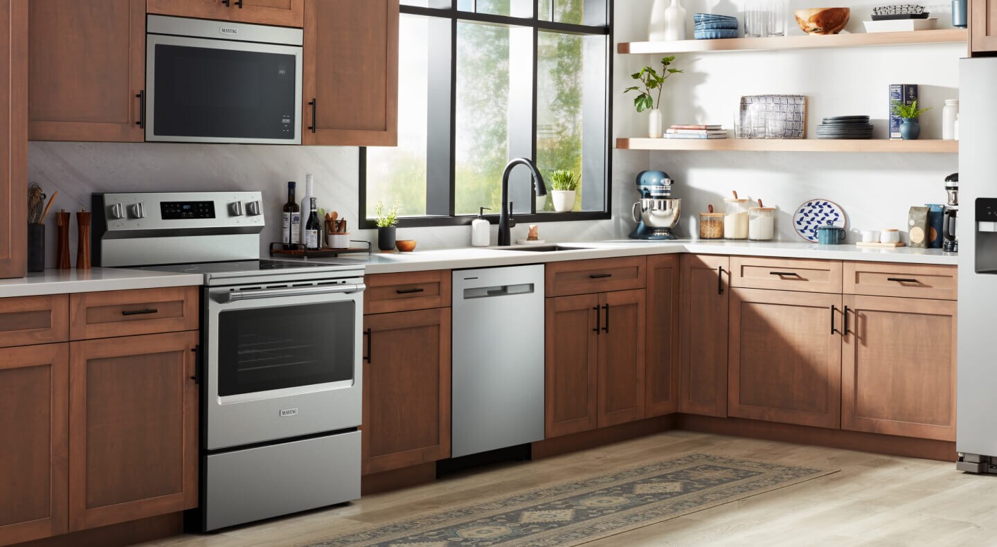 A kitchen with wood paneling and stainless steel appliances, including an oven, microwave and dishwasher