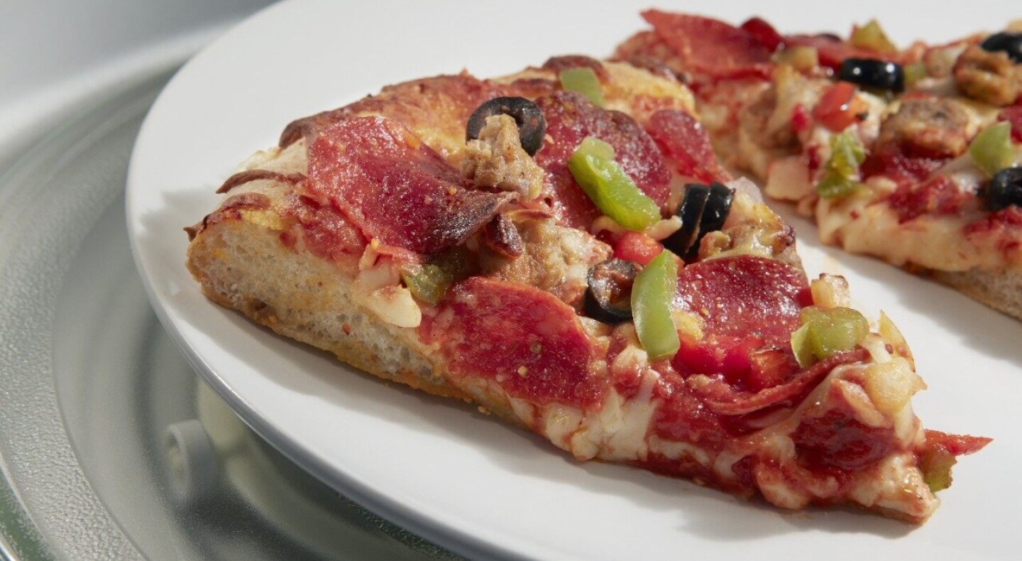 A slice of pizza with pepperoni, black olives and green peppers on top A slice of pizza with pepperoni, black olives and green peppers on top