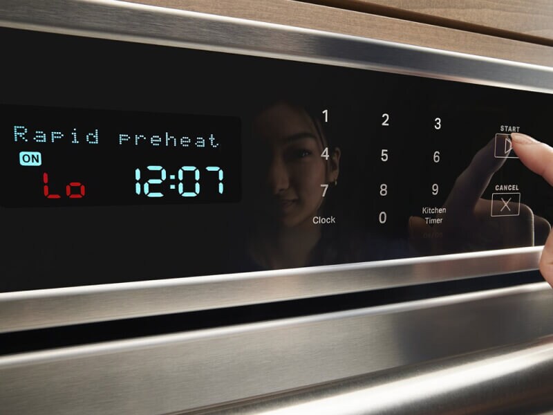 A finger shown pressing the start button on an oven