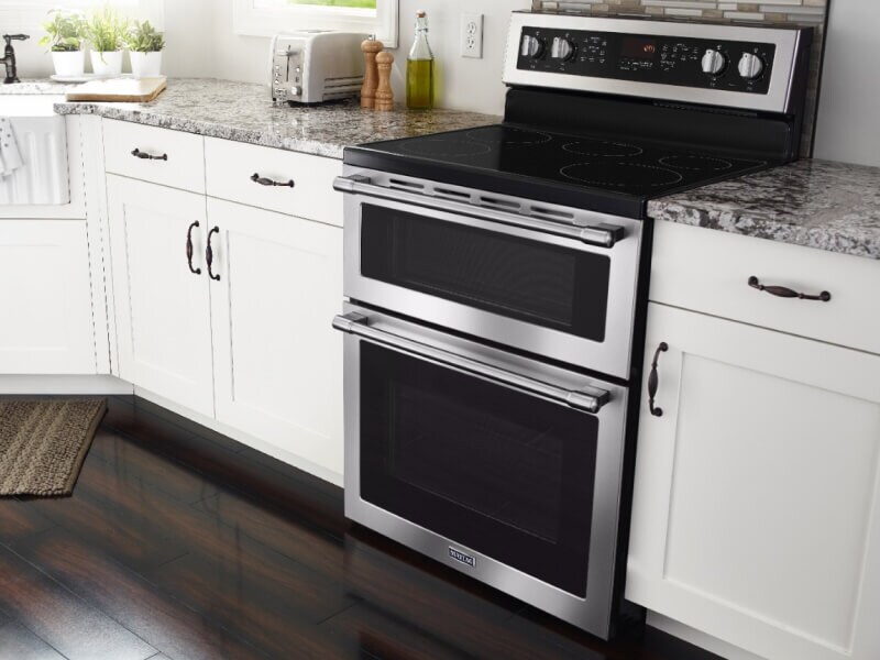 A kitchen with wooden cabinetry, marble countertops and an oven