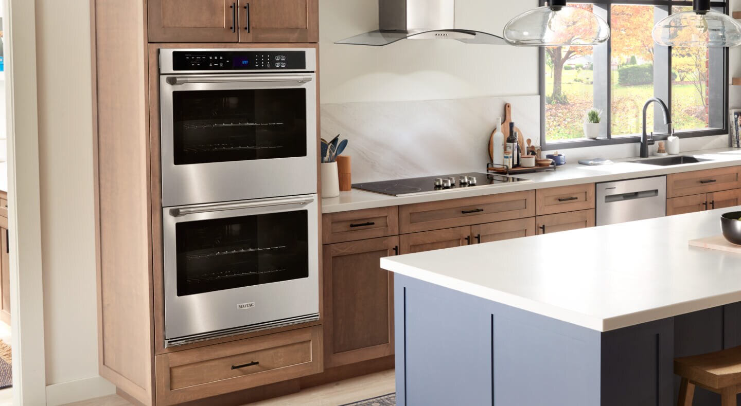 A kitchen with wood cabinetry and a Maytag brand double wall oven