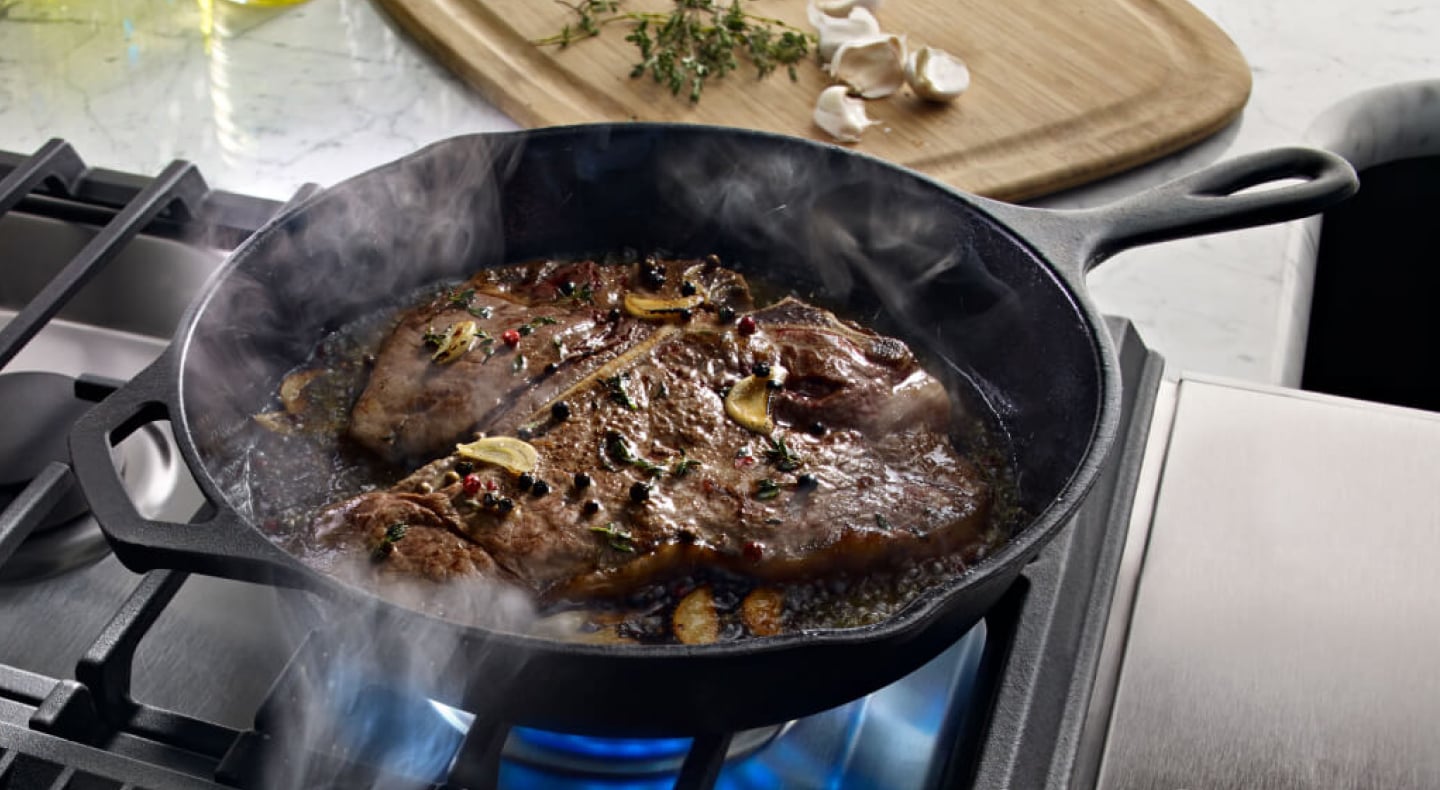 T-bone steak cooking in a cast iron skillet T-bone steak cooking in a cast iron skillet