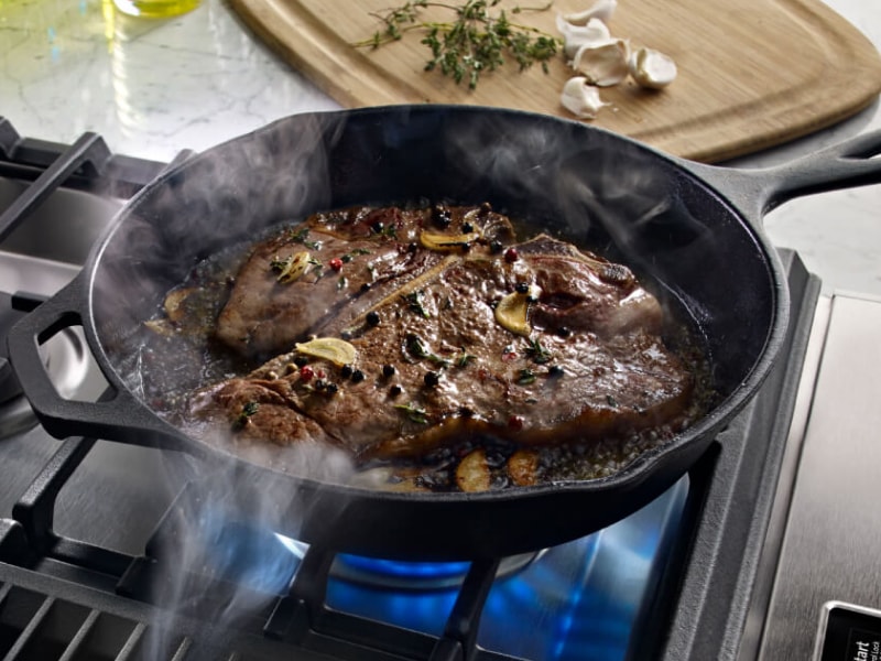 T-bone steak cooking in a cast iron skillet T-bone steak cooking in a cast iron skillet