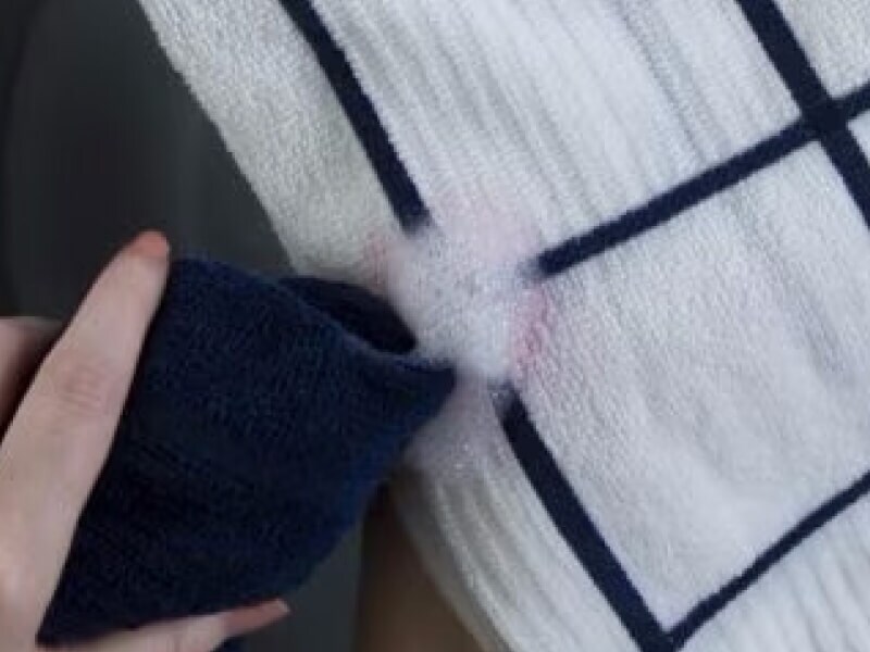 Person spot-treating a stain on a white washcloth