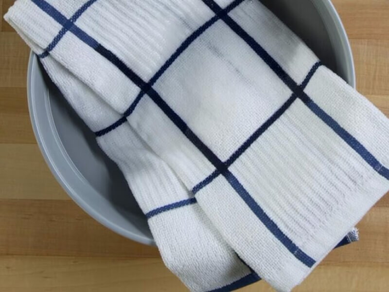 White washcloth soaking in a bowl of water and detergent