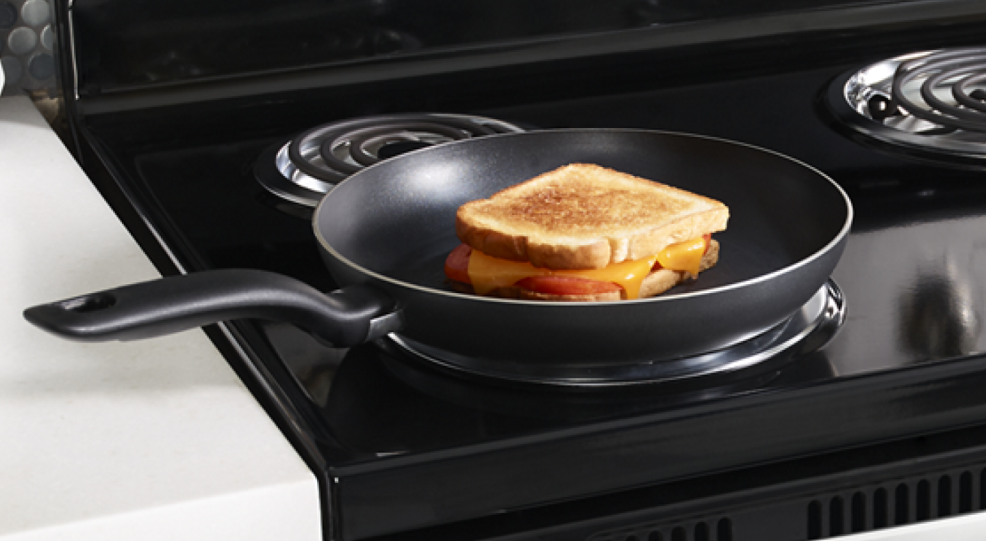 A grilled cheese sandwich in a frying pan on an electric stove with coil burners. A grilled cheese sandwich in a frying pan on an electric stove with coil burners.