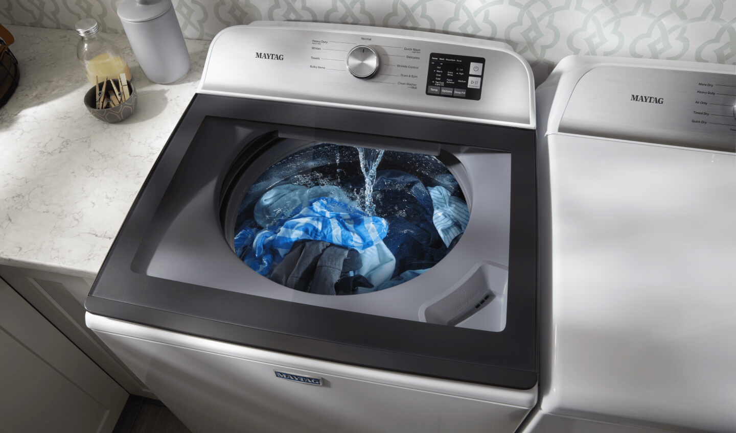Water flowing into the tub of a white Maytag® Top Load Washer full of clothes