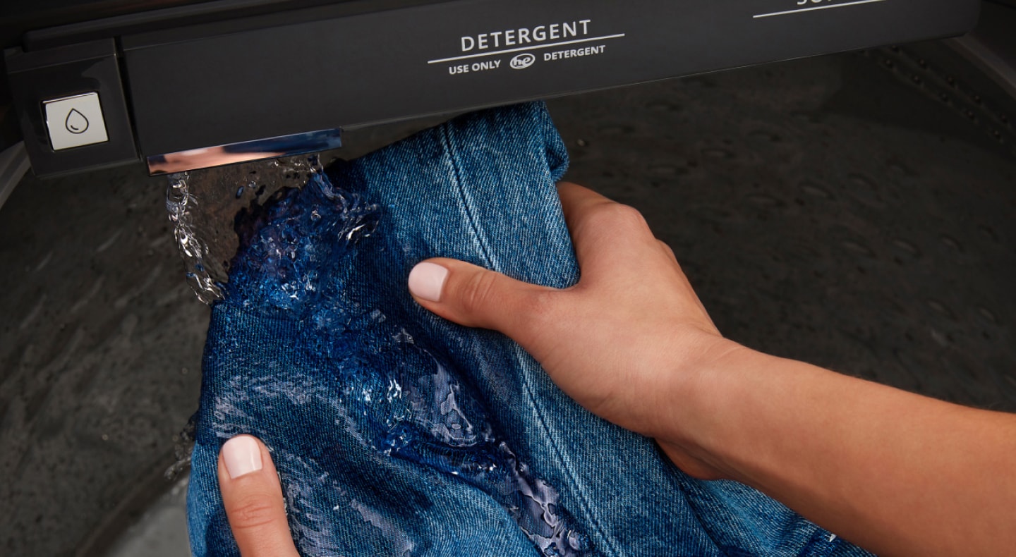 Person rinsing jeans in a Maytag® washer Person rinsing jeans in a Maytag® washer