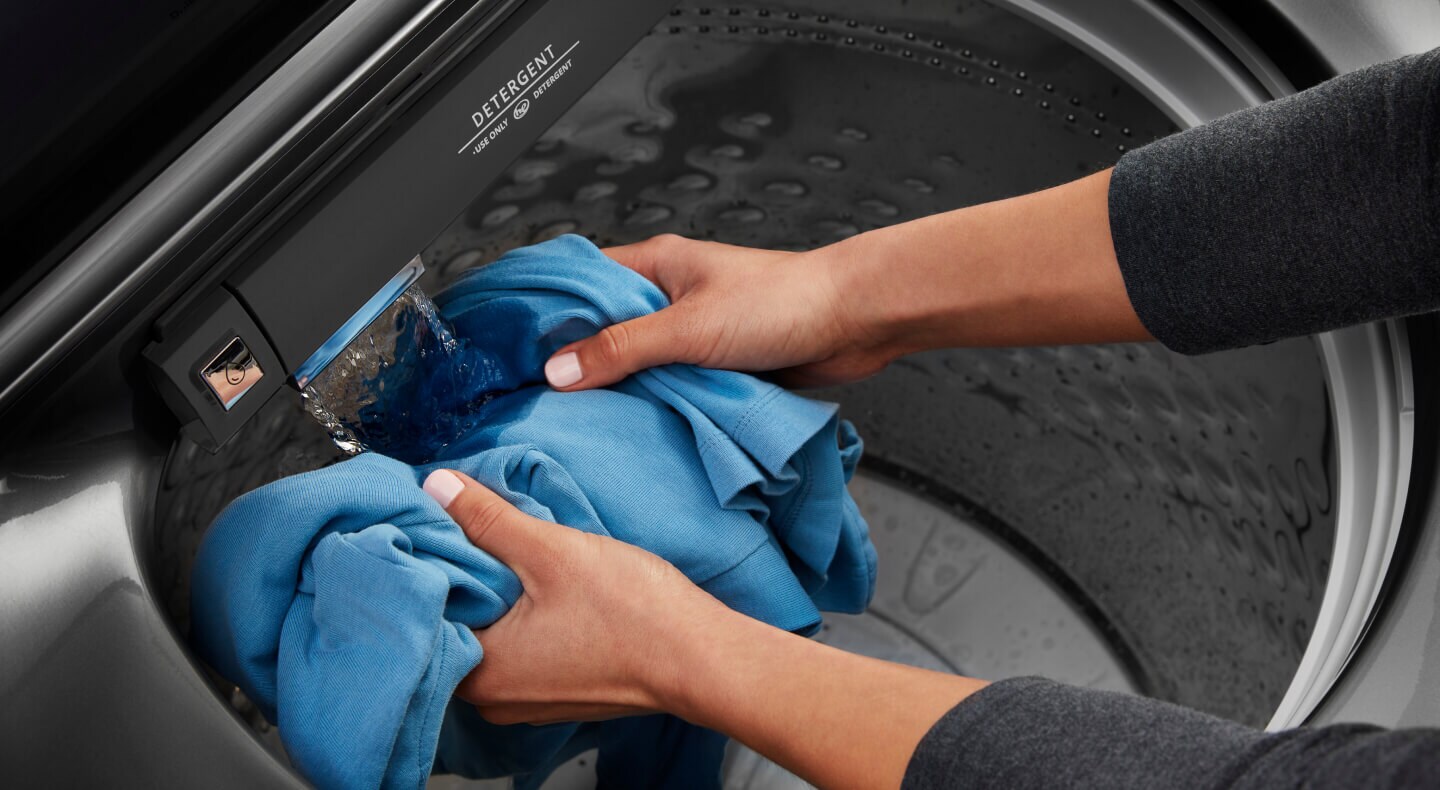 A person rinsing a shirt inside a washing machine
