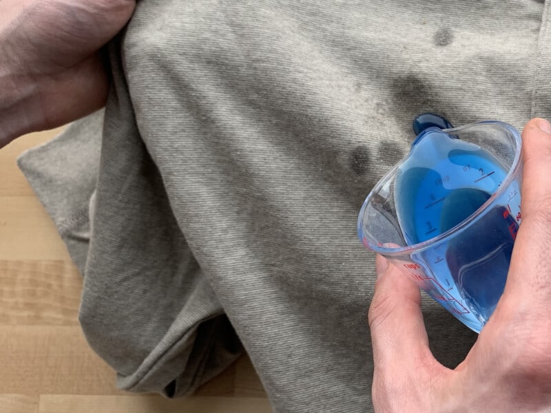 Blue detergent being applied to a gray shirt