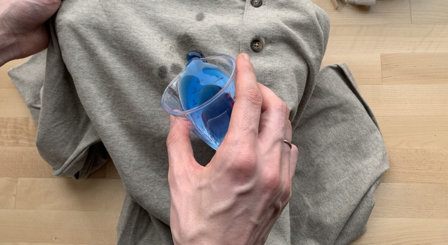 Blue detergent being applied to a gray shirt