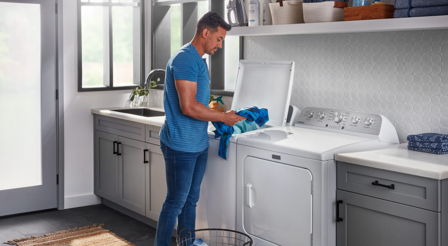 Person unloading blue clothes from a Maytag® top load washing machine