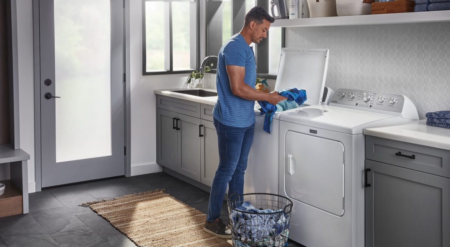 Person loading laundry in a top load washer