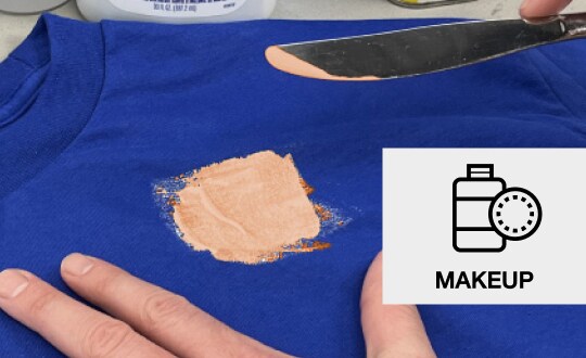 Person scraping makeup off a blue t-shirt