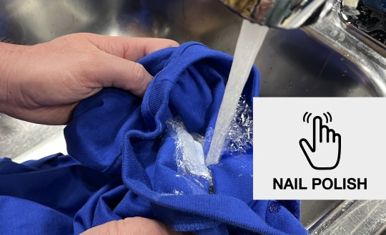 Person rinsing a blue t-shirt under a sink faucet