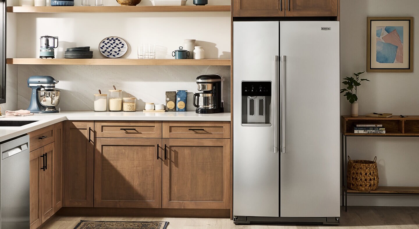 The inside of a kitchen with wooden cabinets and a refrigerator with a water filter