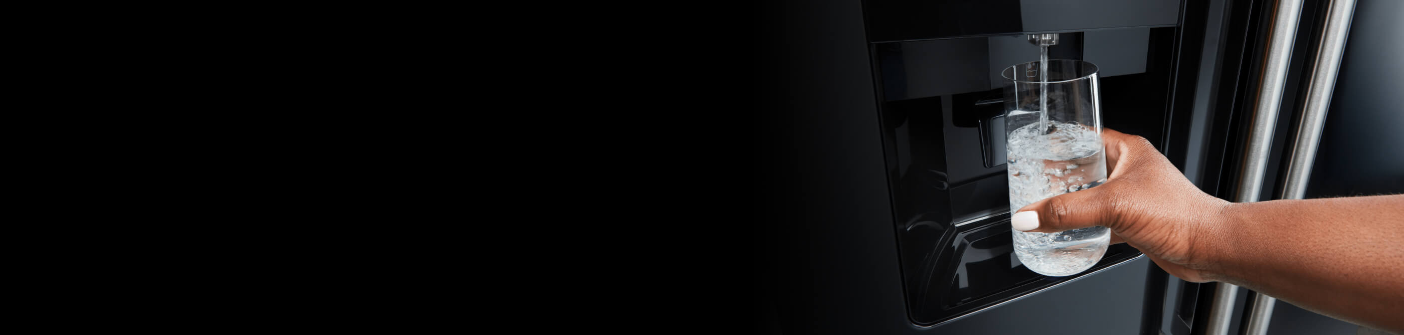 Person filling up their glass with water from a Maytag® refrigerator