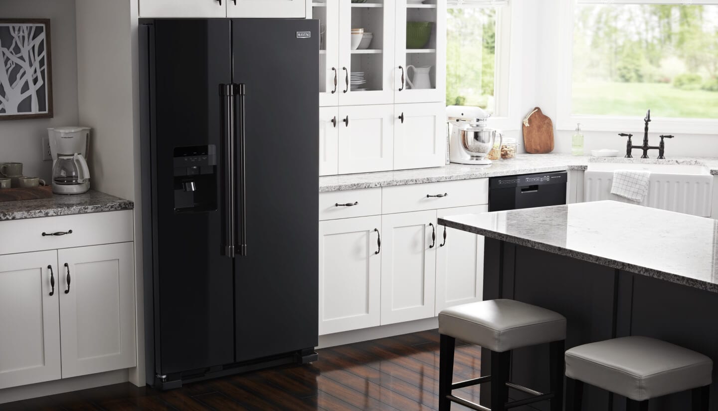 Black Maytag® side-by-side refrigerator inside a kitchen