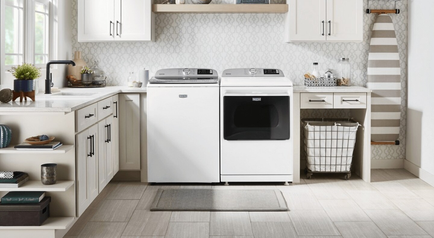 White Maytag® front load washer and dryer set atop pedestals in laundry room
