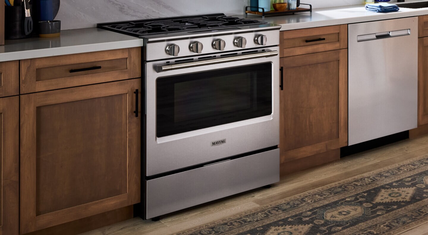 A Maytag® gas range with frying pans on the cooktop in a modern kitchen