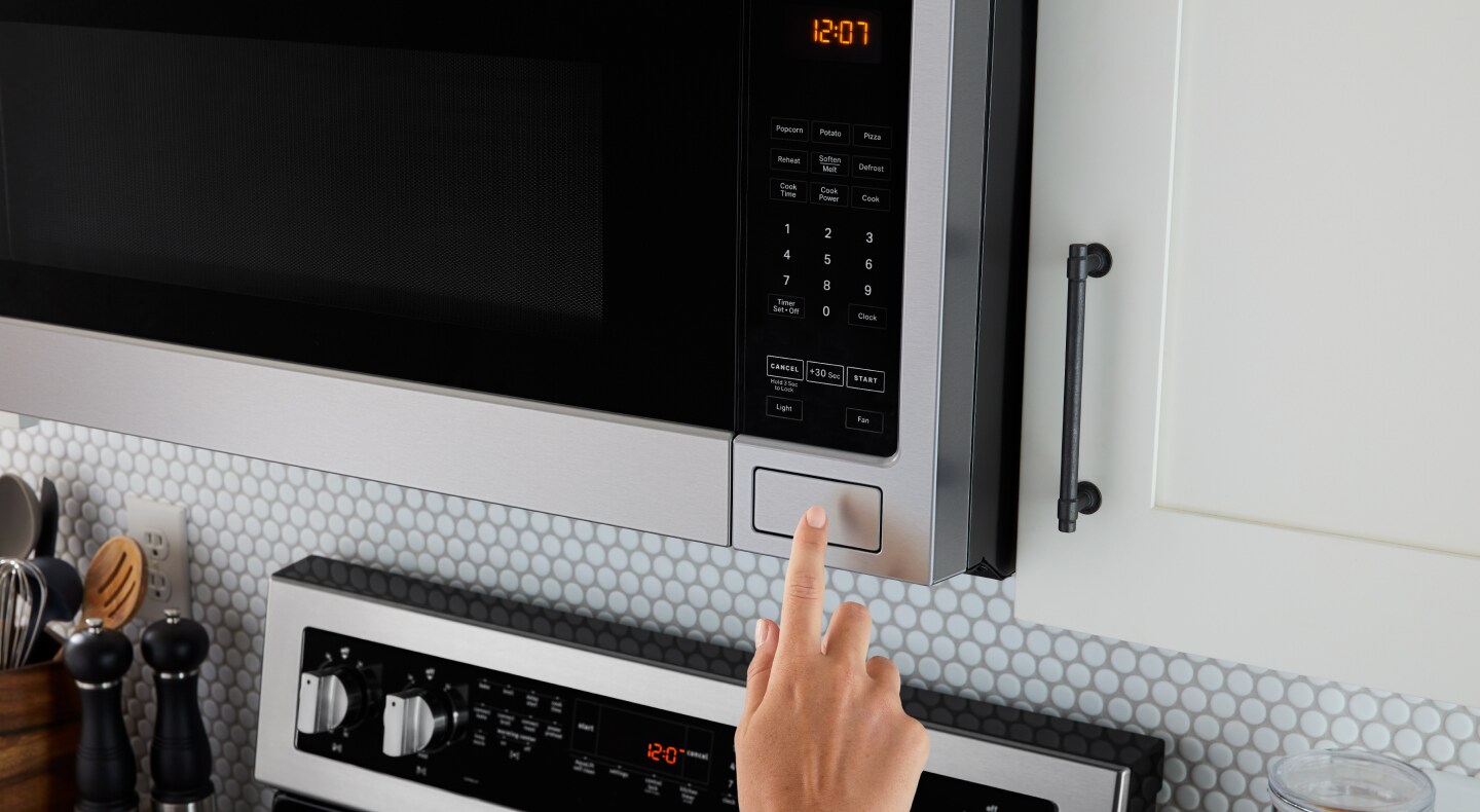 Person pressing open button on microwave Person pressing open button on microwave