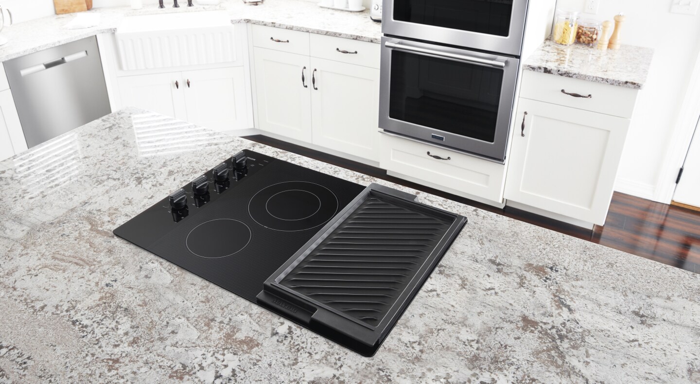 Electric stovetop with built-in griddle on granite island countertop Electric stovetop with built-in griddle on granite island countertop