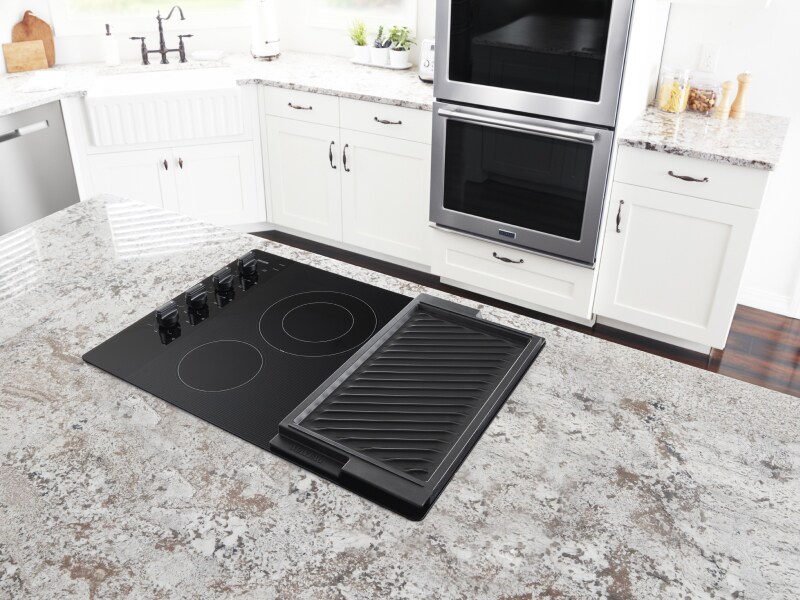 Electric stovetop with built-in griddle on granite island countertop Electric stovetop with built-in griddle on granite island countertop