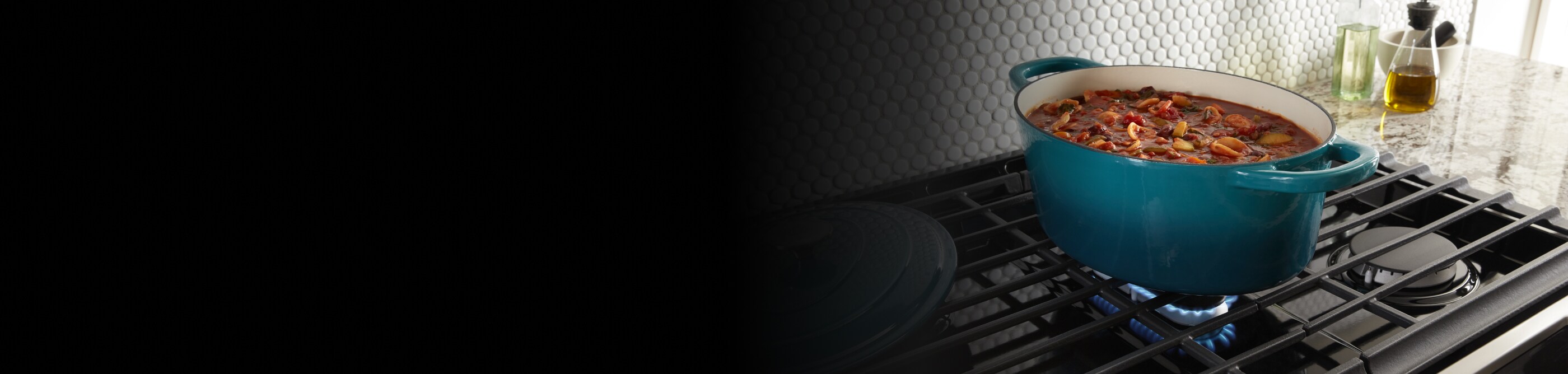 Blue dutch oven full of stew on iron grates above gas burner 