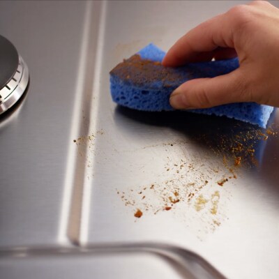 Person wiping off a gas stovetop