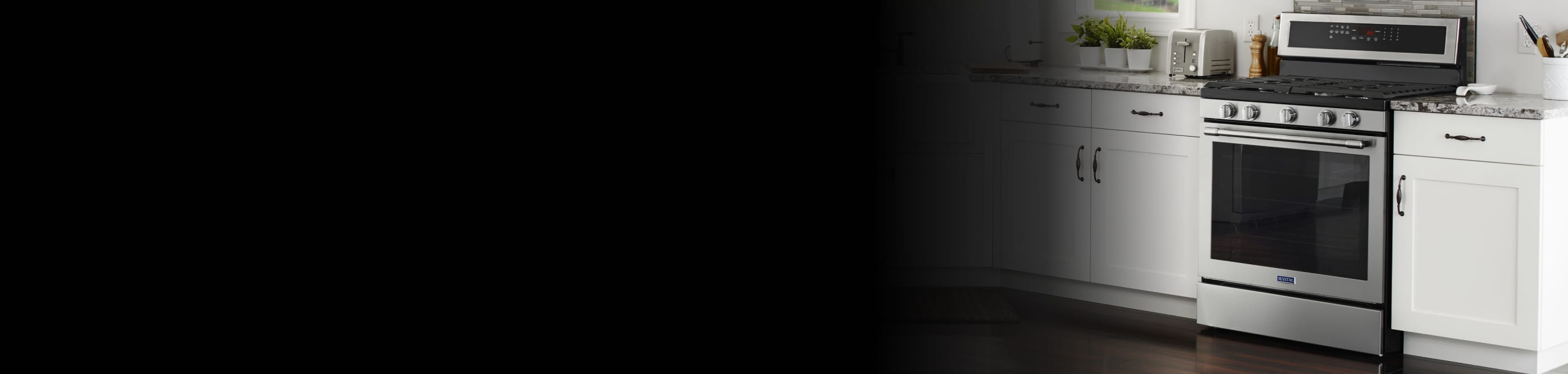 A modern white kitchen with Maytag® stainless steel appliances