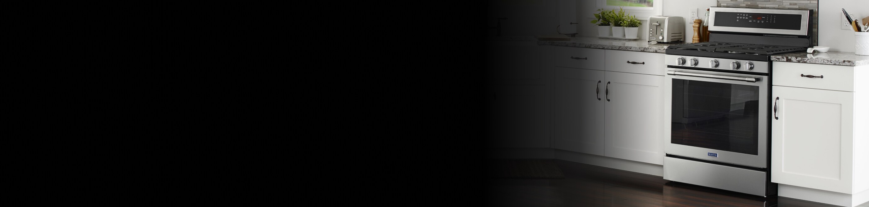 A modern white kitchen with Maytag® stainless steel appliances