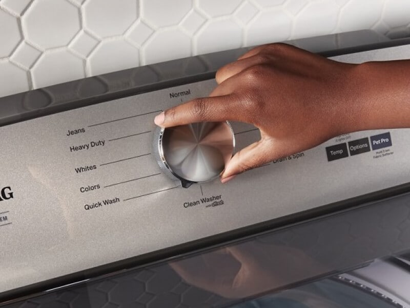A person selecting a wash setting on a Maytag® top load washer