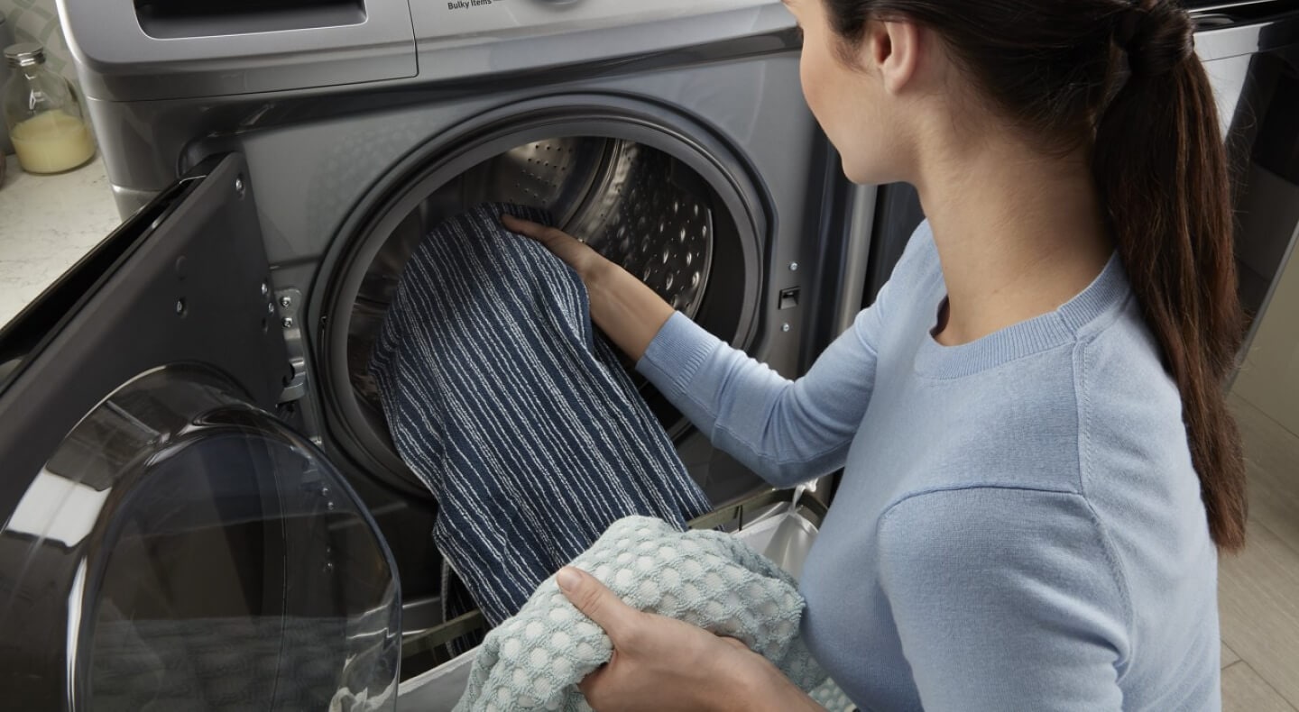 A person adding laundry to a Maytag® front load washer A person adding laundry to a Maytag® front load washer