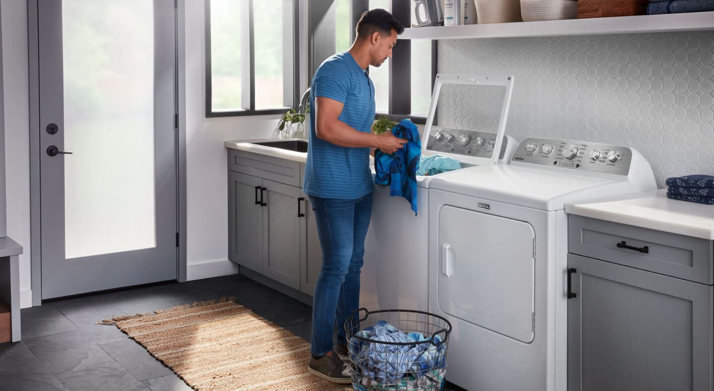 Person doing laundry with a Maytag® washer and dryer set Person doing laundry with a Maytag® washer and dryer set