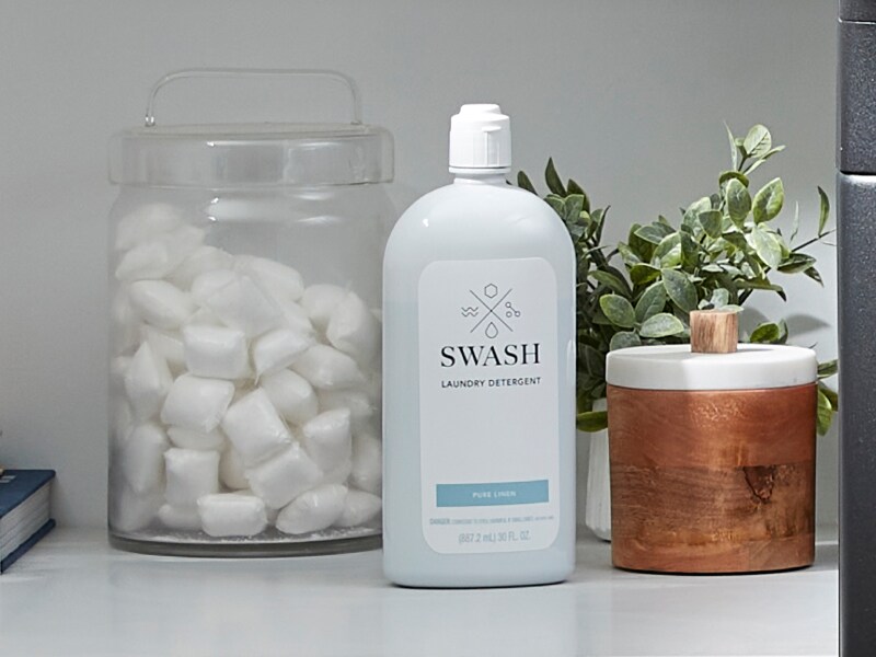 Swash® detergent next to a glass jar of laundry pods Swash® detergent next to a glass jar of laundry pods
