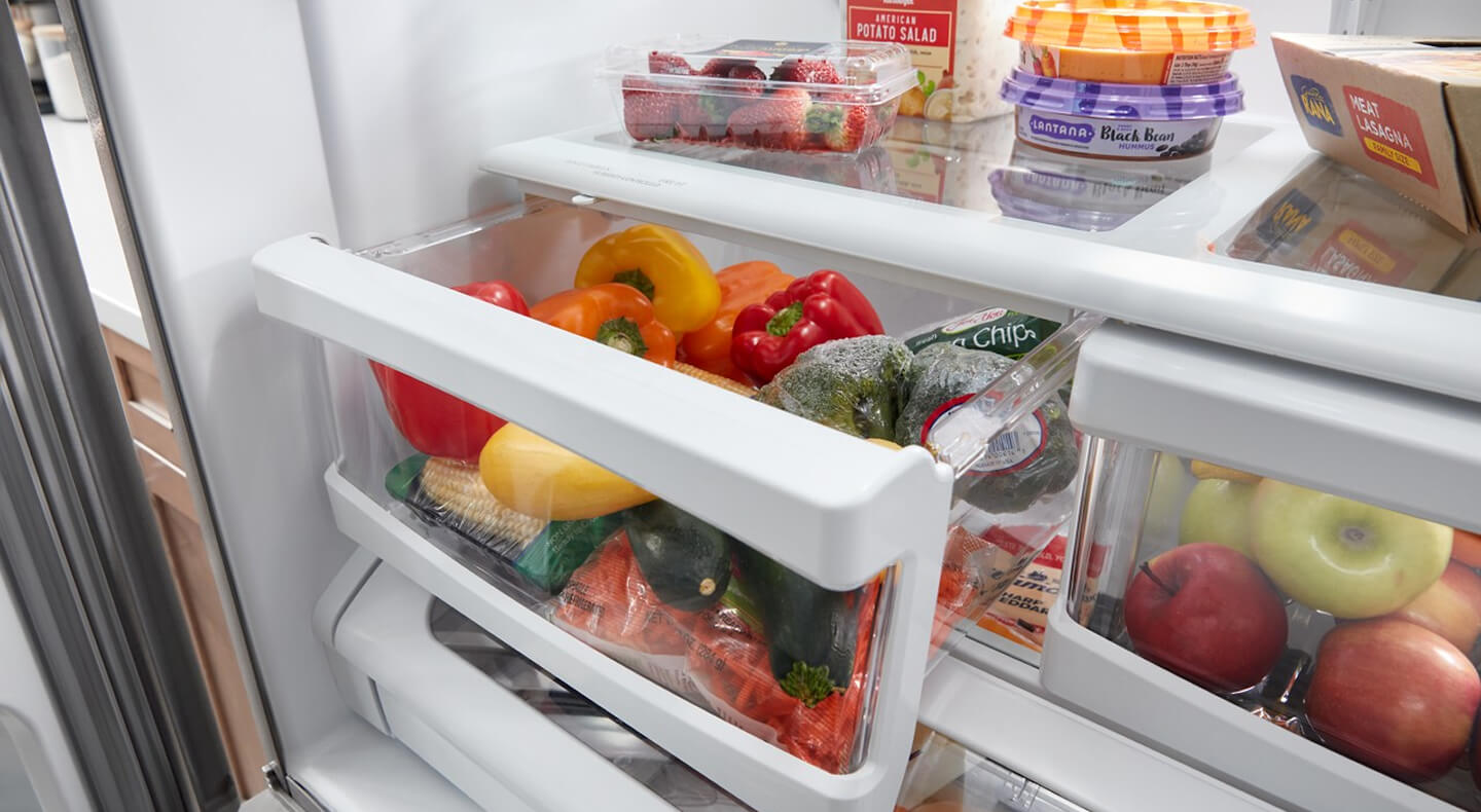 A close-up of an open crisper drawer with produce inside