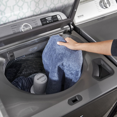 Person loading clothes into Maytag® top load washer